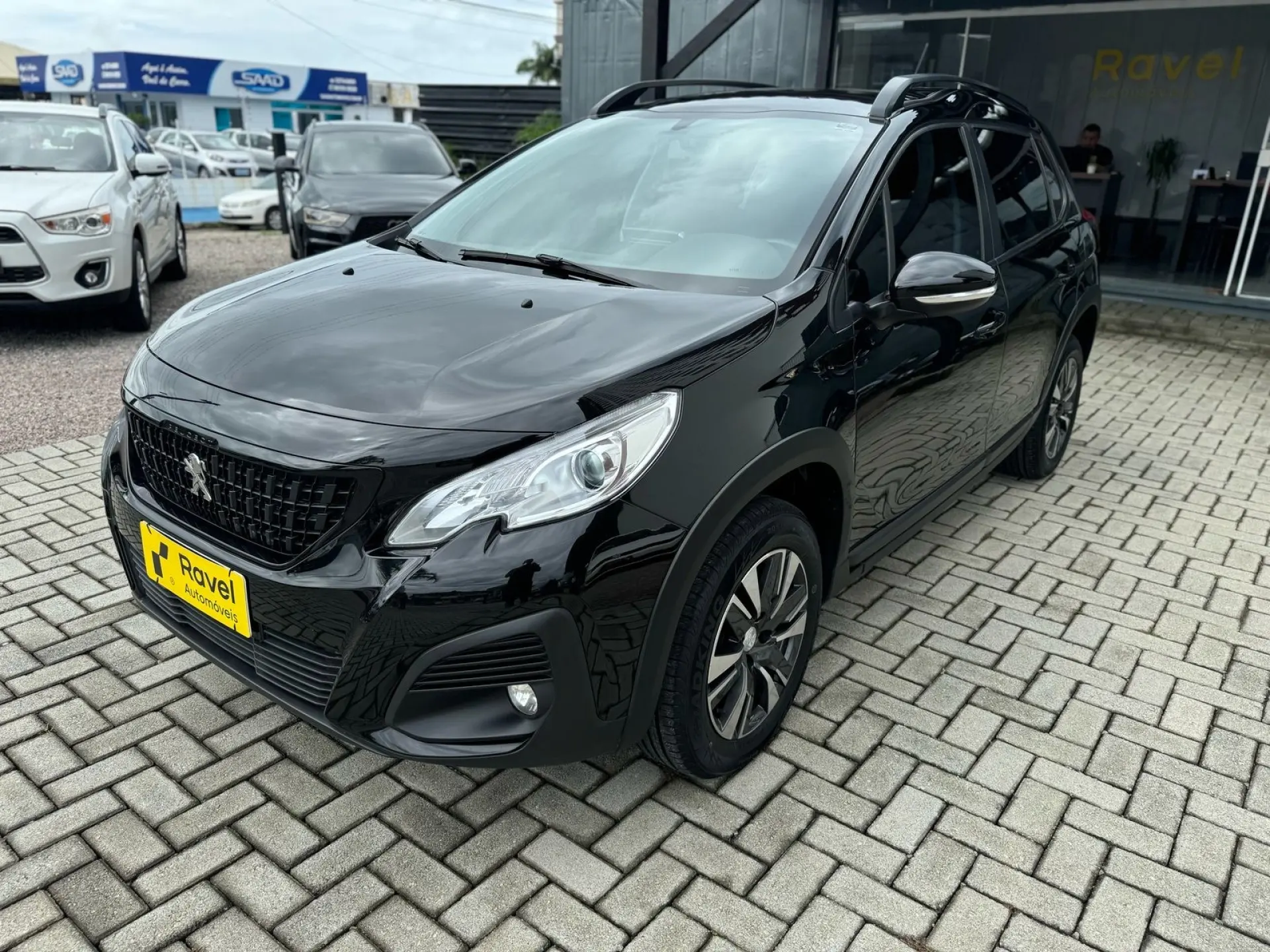 Peugeot 2008 preto no pátio de bloquete da Ravel, diante da fachada da loja